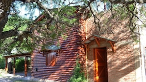 Ein rustikales Blockhaus mit Ziegelanbau, umgeben von Bäumen.