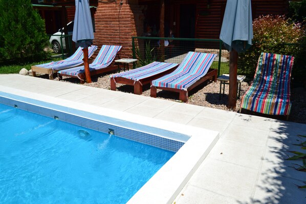 Una piscina al aire libre, sillones reclinables de piscina