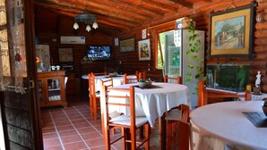 Eine rustikale Holzhütte mit einem Essbereich, der runde Tische und Holzstühle beherbergt.