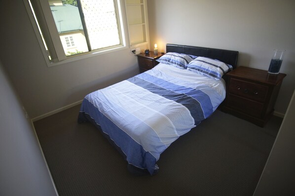 A bedroom with a bed, nightstand, and bedside table.