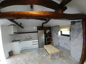 Una cocina compacta con armarios blancos, un horno integrado y una pequeña mesa de madera.