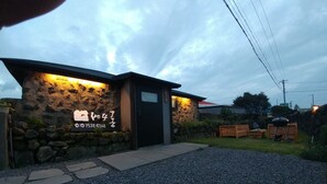 Edificio con fachada de piedra y puerta negra, que muestra un número de contacto y un logotipo.