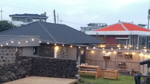 Un espacio de descanso rústico al aire libre con muros de piedra, bancos de madera y una terraza de madera.