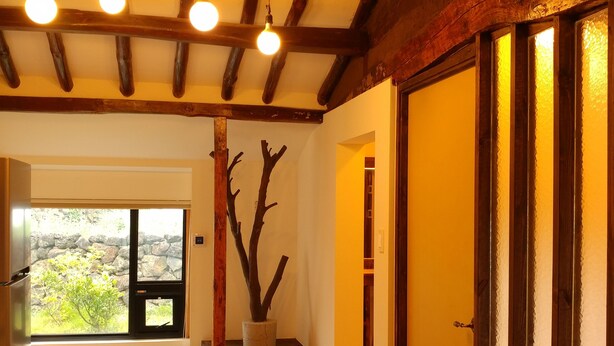 Habitación con techo de madera, un ventanal y vistas al exterior con vegetación.