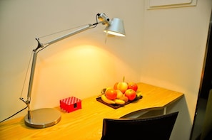 A desk with a lamp, a fruit bowl, and a red polka-dotted box.