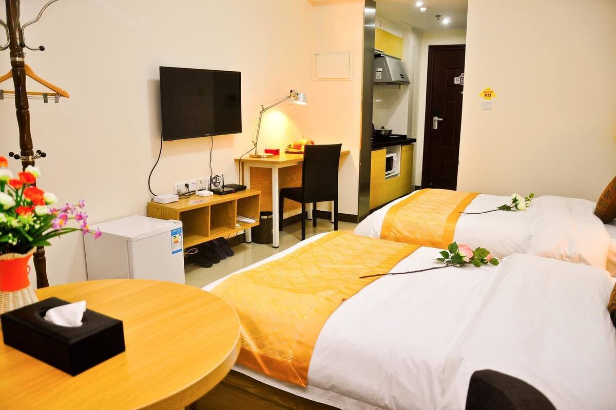 Une chambre d’hôtel avec deux lits, un bureau, une chaise, une télévision et une kitchenette.