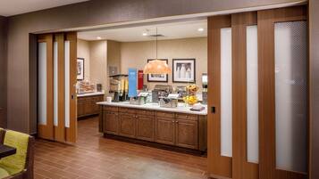 A modern kitchen with wooden cabinets, a central island, and a hanging pendant light.