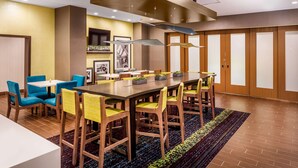 A conference room with a long table, blue and yellow chairs, and a patterned rug.