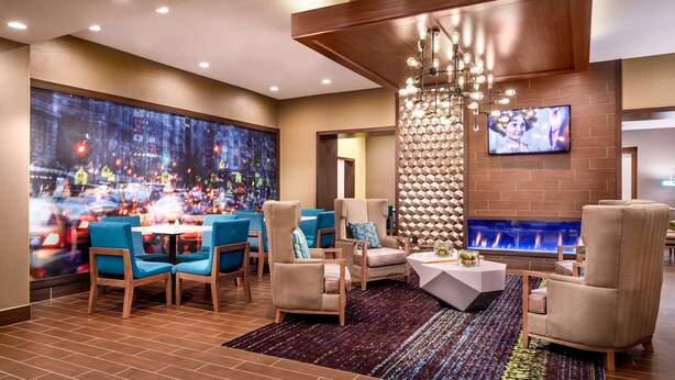 A modern lounge area with a large TV, comfortable seating, a fireplace, and a cityscape view.
