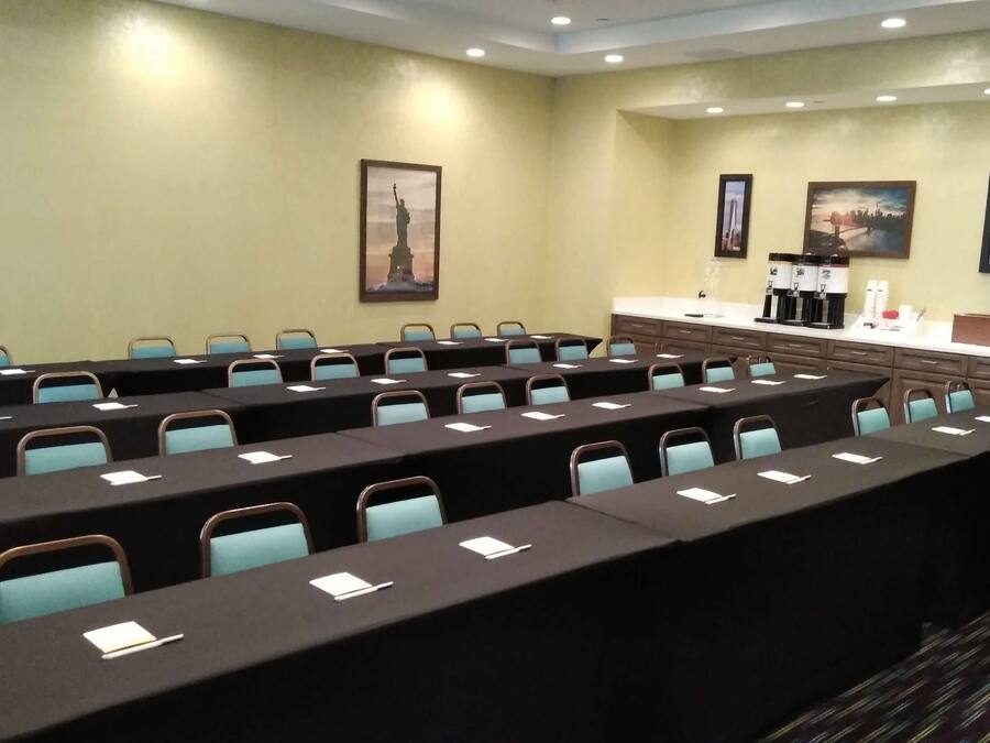 A conference room with long tables, chairs, and a coffee station.