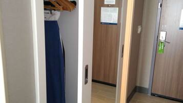 A hallway with a wooden floor, a mirror on the wall, and a door with a green lock.