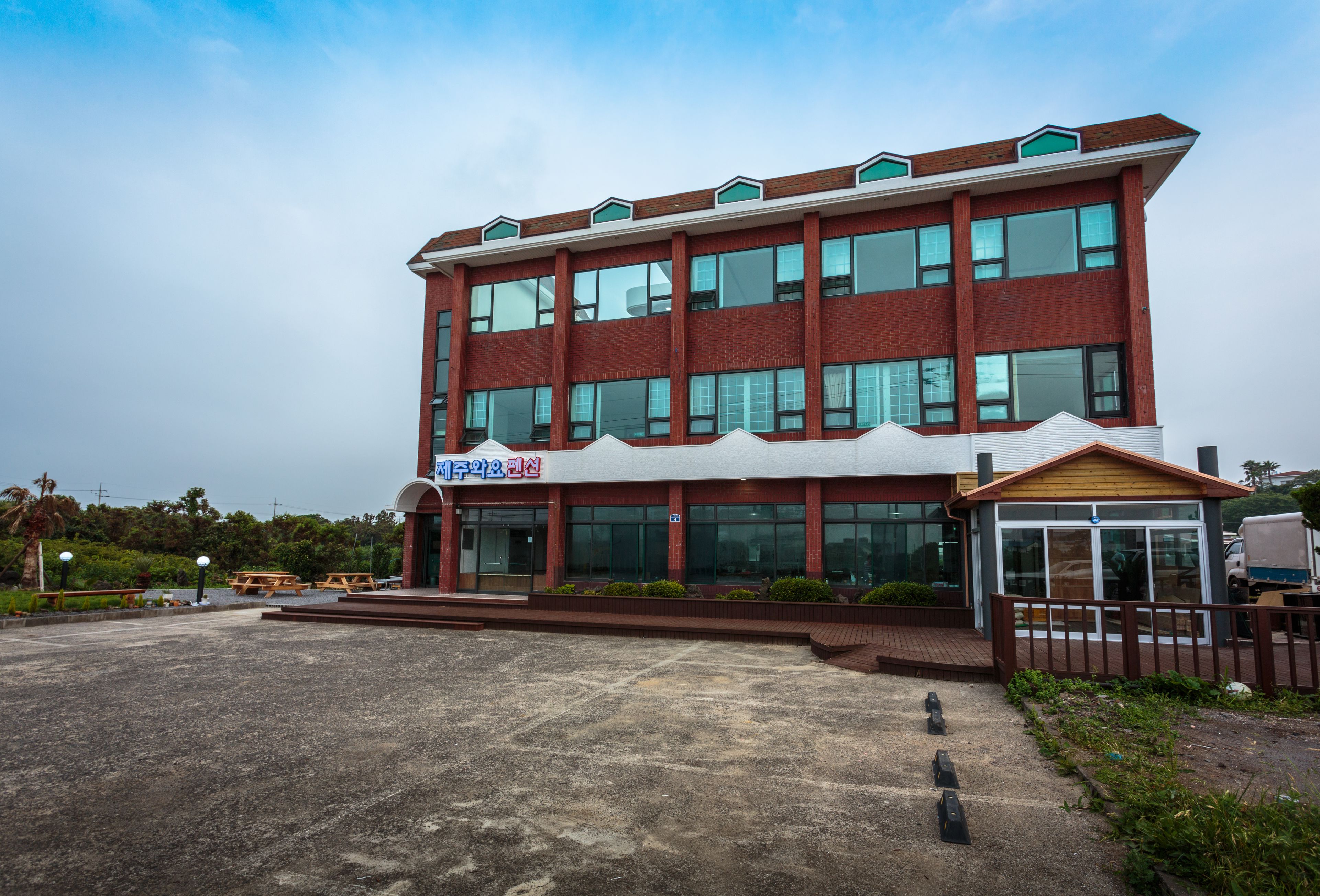 Un edificio de varios pisos con fachada de ladrillo rojo, ventanas grandes y un área de entrada cubierta.