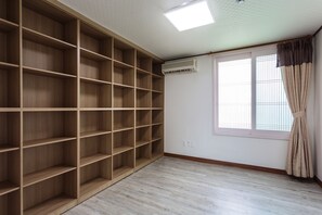 Um quarto com uma estante de madeira grande, uma janela com cortinas e um aparelho de ar condicionado na parede.