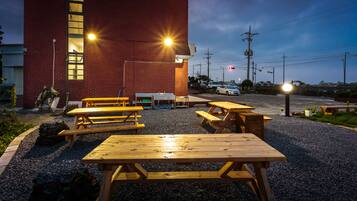 A building with a red brick exterior and multiple wooden picnic tables arranged in front.