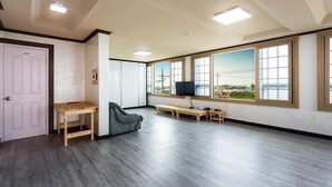 Una habitación amplia con un gran ventanal, televisor, escritorio y una silla.