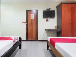 A hotel room with two beds, a TV mounted on the wall, a wooden wardrobe, and a desk with a chair. - Vaccinated Staff - OYO 567 Blue Horizon Hostel (Dumaguete)