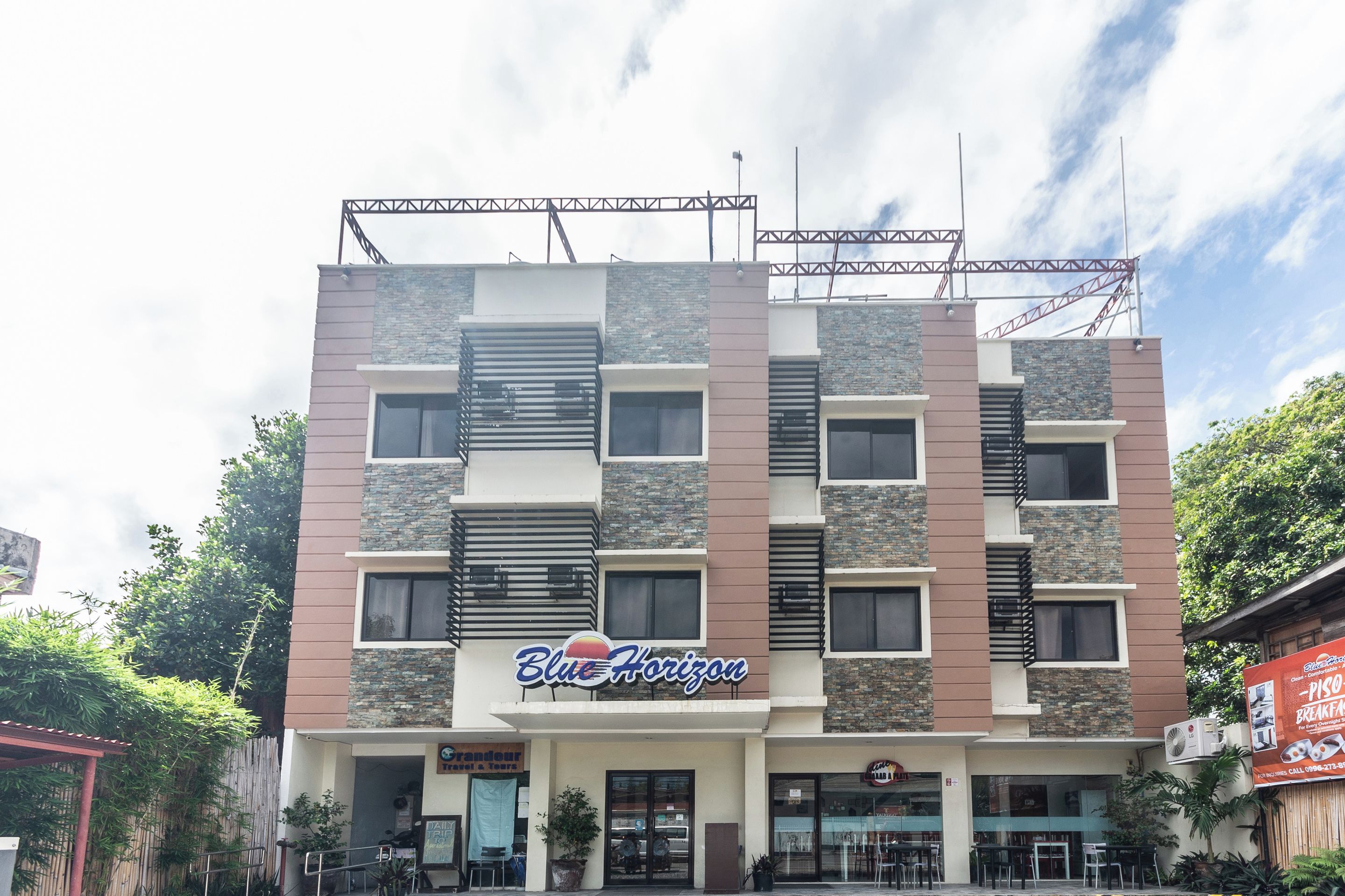 Een meerlaags hotel met een moderne gevel, met een opvallend bord met de tekst 'Blue Horizon'.