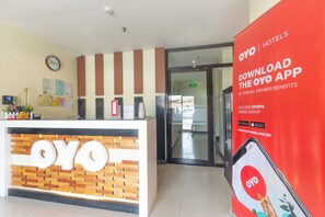 A reception desk with a wooden and brick design, a clock, and a digital display. - Vaccinated Staff - OYO 567 Blue Horizon Hostel (Dumaguete)