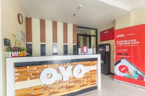 En receptionsdisk med logotypen ”OYO” och en röd reklamaffisch för OYO-appen.