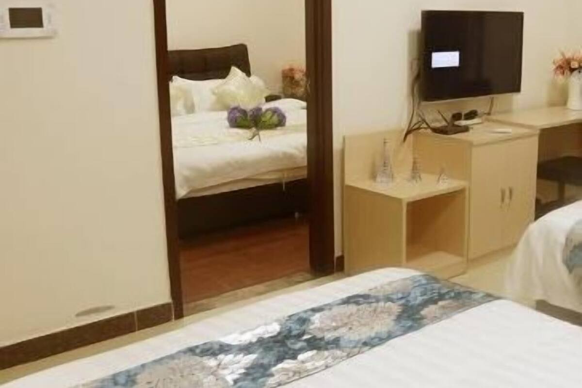 Una habitación de hotel con una cama, televisión, escritorio con computadora y espejo.