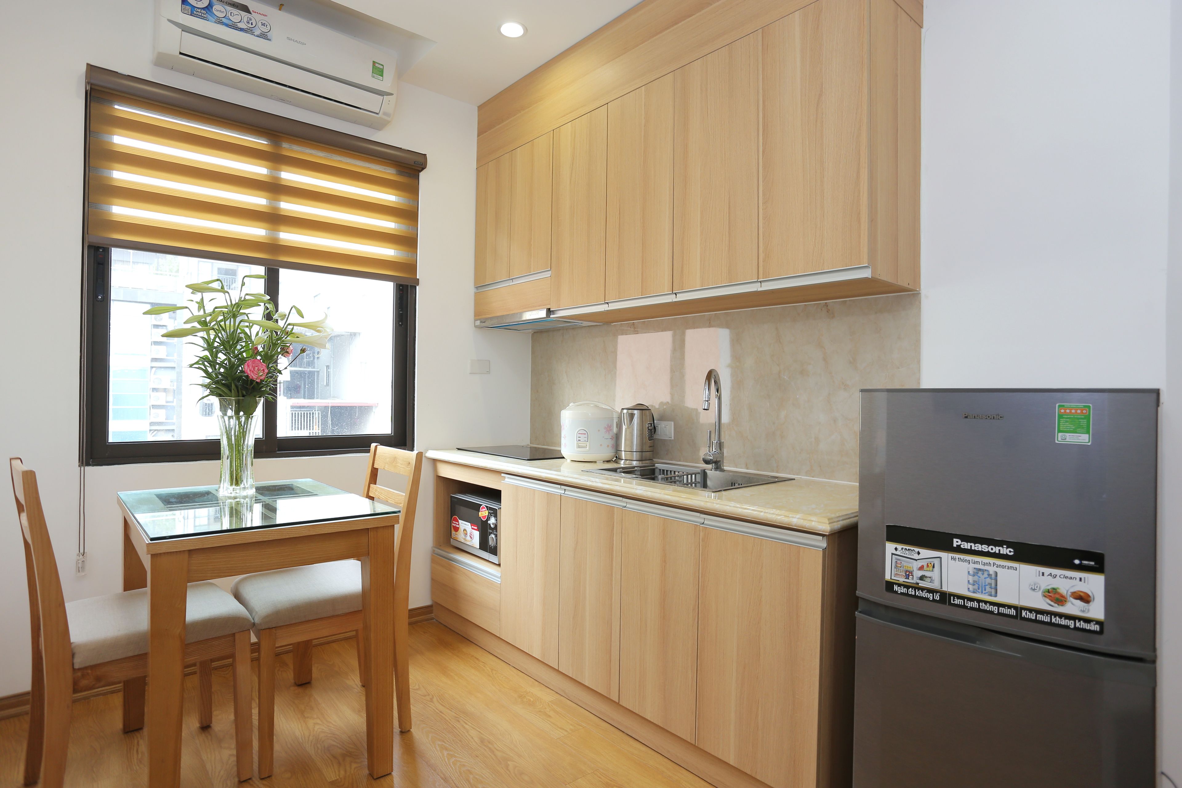A modern kitchen with wooden cabinets, a built-in oven, a refrigerator, and a dining table with chairs.