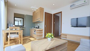 Een moderne woonkamer met een houten salontafel, een bank en een aan de muur bevestigde televisie.