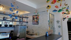 A kitchen with a brick wall, a refrigerator, a sink, and various kitchen utensils. - Sea Turtle Hostel - Adults Only (Ko Chang)