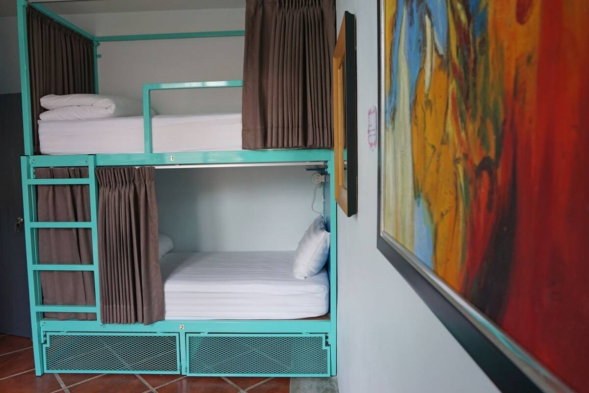 A bunk bed room with curtains, a painting on the wall, and tiled flooring.