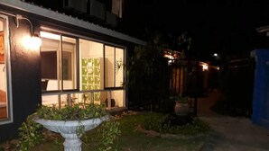 A modern building with large windows, a white decorative planter, and a well-maintained garden at night. - Sea Turtle Hostel - Adults Only (Ko Chang)