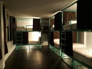 A corridor with bunk beds, each with a window and curtains.