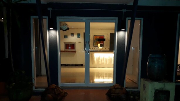 A house entrance with a glass door leading to a well-lit interior. - Sea Turtle Hostel - Adults Only (Ko Chang)