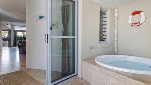 A modern bathroom with a bathtub, a glass shower enclosure, and a towel rack. - Jades on Lawson 2 (Byron Bay)
