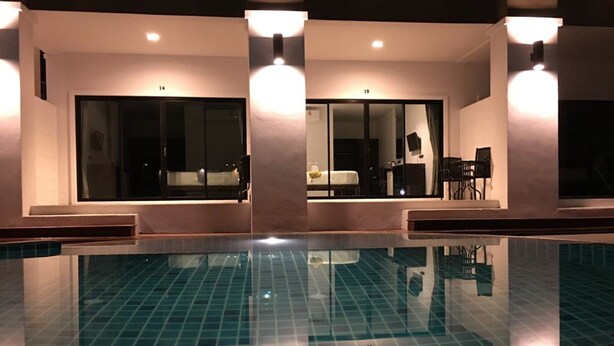 Ein Pool mit Fliesenboden, umgeben von einem Gebäude mit großen Fenstern und einer Sitzgelegenheit.