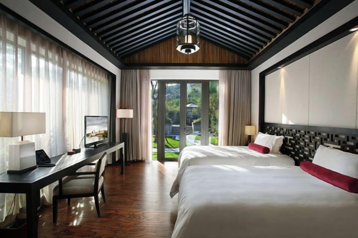 Habitación de hotel con una cama grande, un escritorio y vistas a zonas verdes.