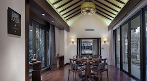 A modern dining area with a wooden table and chairs, large windows, and a ceiling with wooden beams and a skylight. - Elite Spring Villas (Quanzhou)