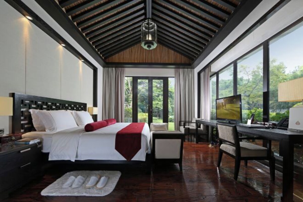 A modern hotel room with a large bed, a desk, and a view of the outdoors.
