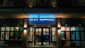 Un bâtiment sur lequel on peut lire l’inscription « BAAN NOPPADOL » et la formule « Un lieu où l’on trouve une ambiance positive ».