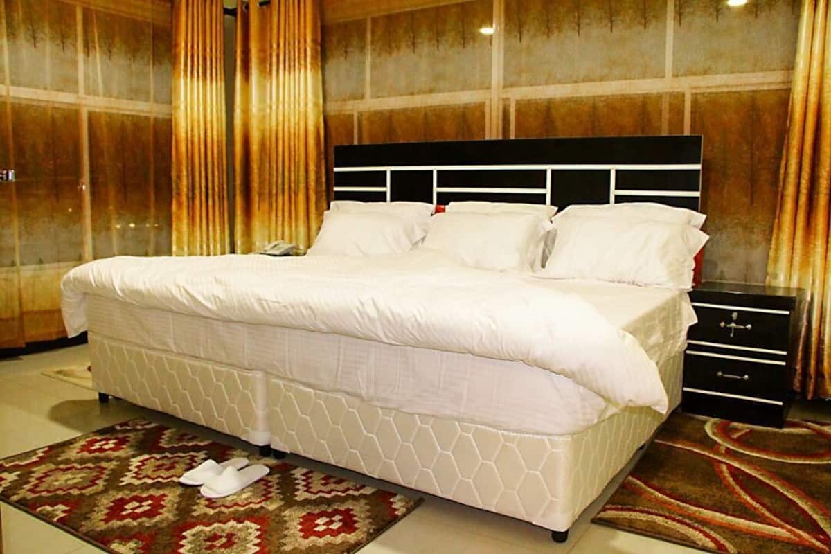 A hotel room with a large bed, a bedside table, and a carpeted floor.