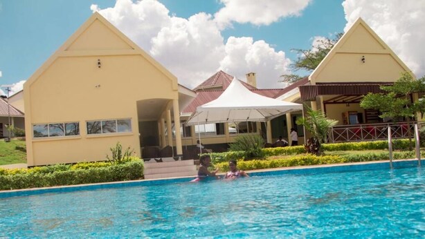 Zona de piscina con dos edificios amarillos, uno con un patio cubierto y otro con techo rojo.
