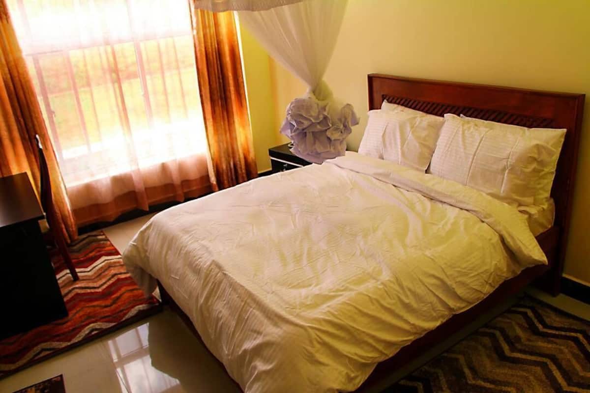 A neatly made bed with white linens, a wooden headboard, and a bedside table with a lamp.