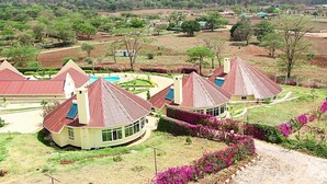 Un complejo turístico con varias edificaciones de techos rojos, rodeado de jardines ajardinados y una piscina.