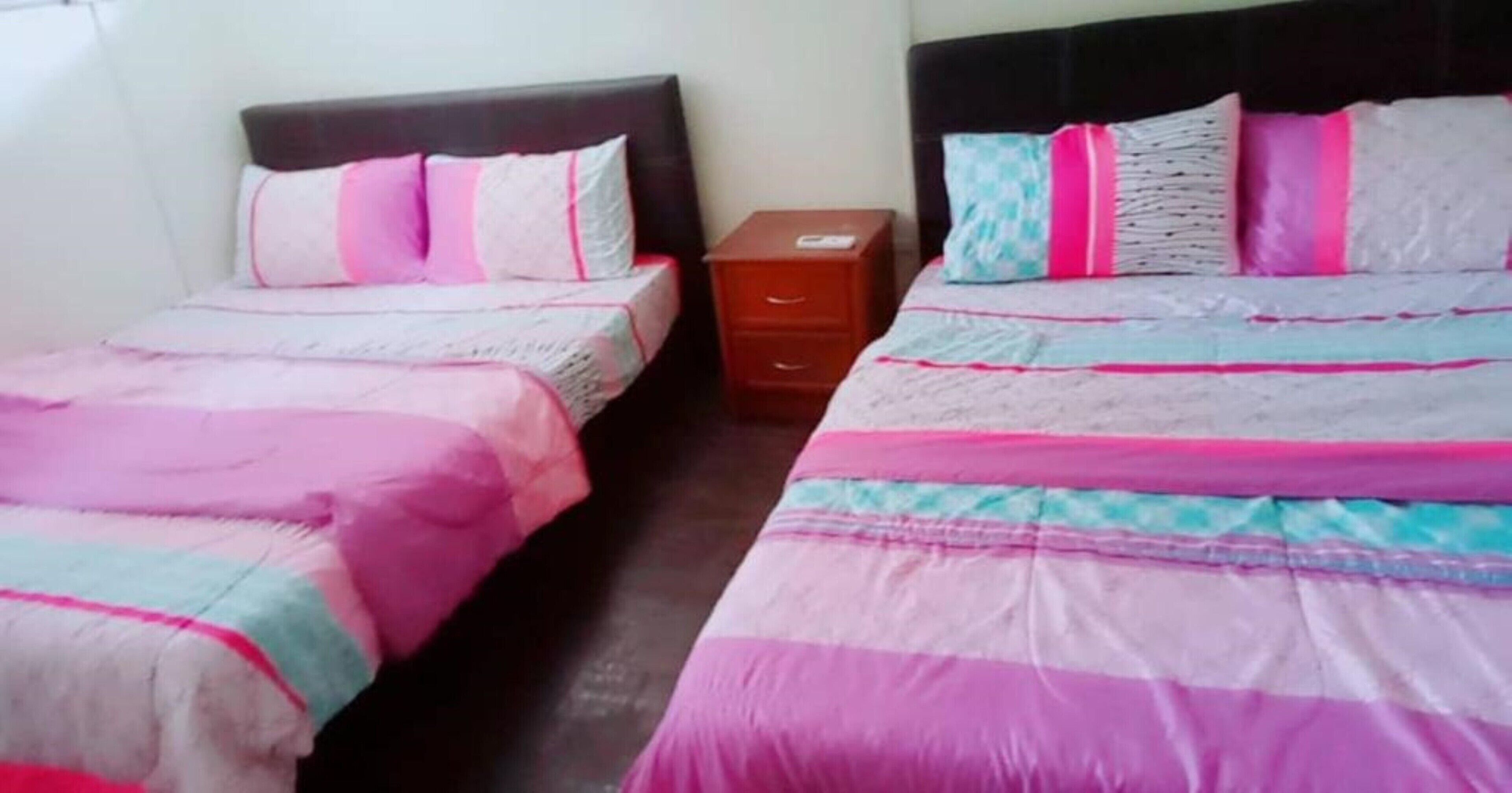 Een slaapkamer met twee bedden, elk met hoofdeinde, nachtkastje en ladekast.