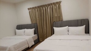 A hotel room with two single beds, each with a striped headboard and white bedding.