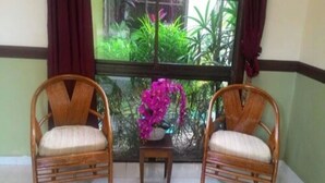 Two wicker chairs with cushions, a small table, and a window with curtains.