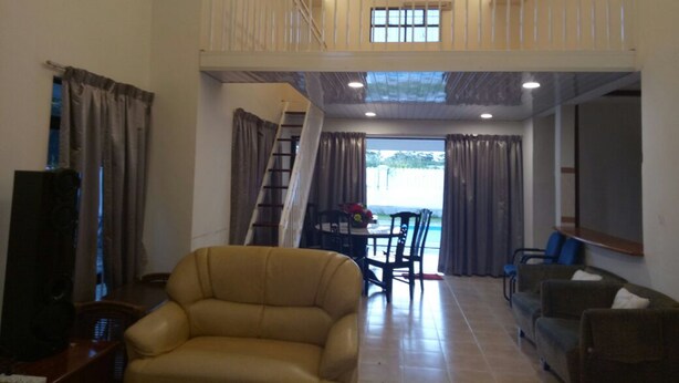 A spacious living area with a high ceiling, a balcony, a dining area, and a view of the outdoors.