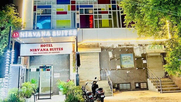 Ein Hotel mit leuchtendem Neonzeichen, einem sichtbaren Eingang und einem abgestellten Motorrad.