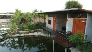 A modern houseboat with a deck, outdoor seating, and a small garden area with plants and a pond. - Panwana Resort (Rayong)