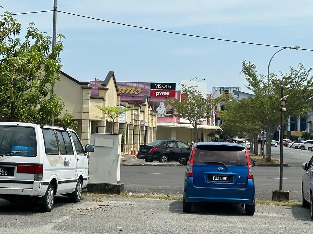 A street view with parked cars, a building with signage for 'Visions' and 'Pyrex', and a clear sky.
