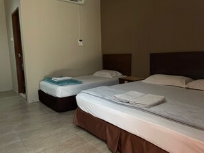 A hotel room with two beds, a wooden floor, and a small bedside table with a lamp. - Baron Waterfront Hotel (Langkawi)