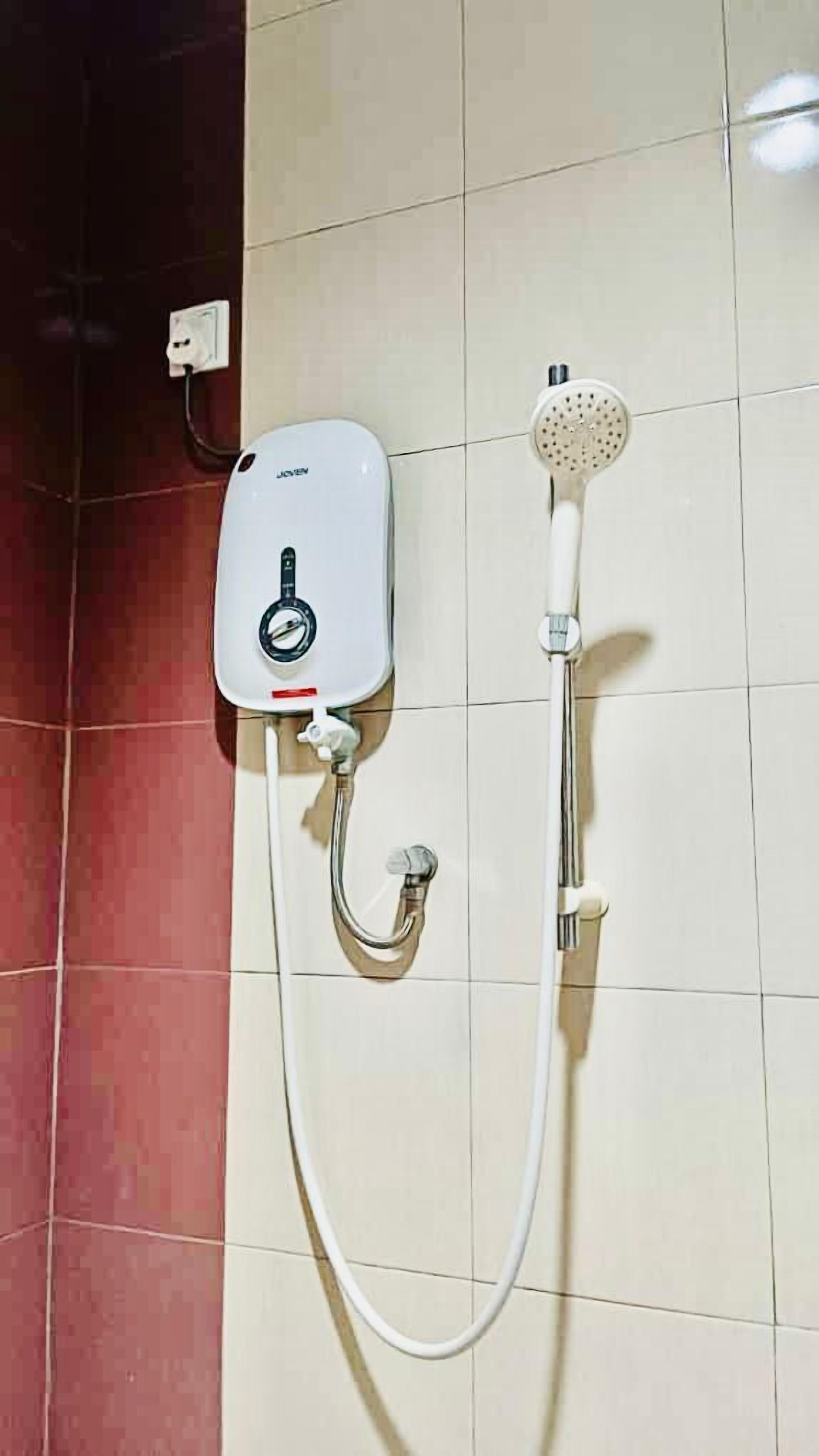 A shower with a control panel and a handheld showerhead mounted on the wall.